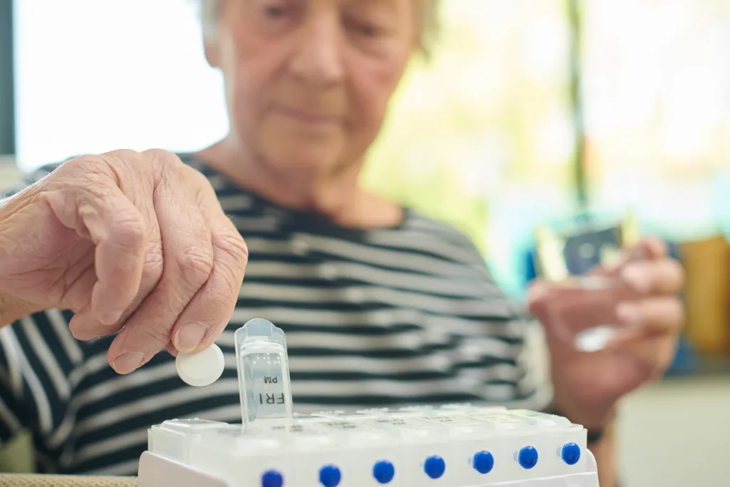 Elderly woman holding a small pill