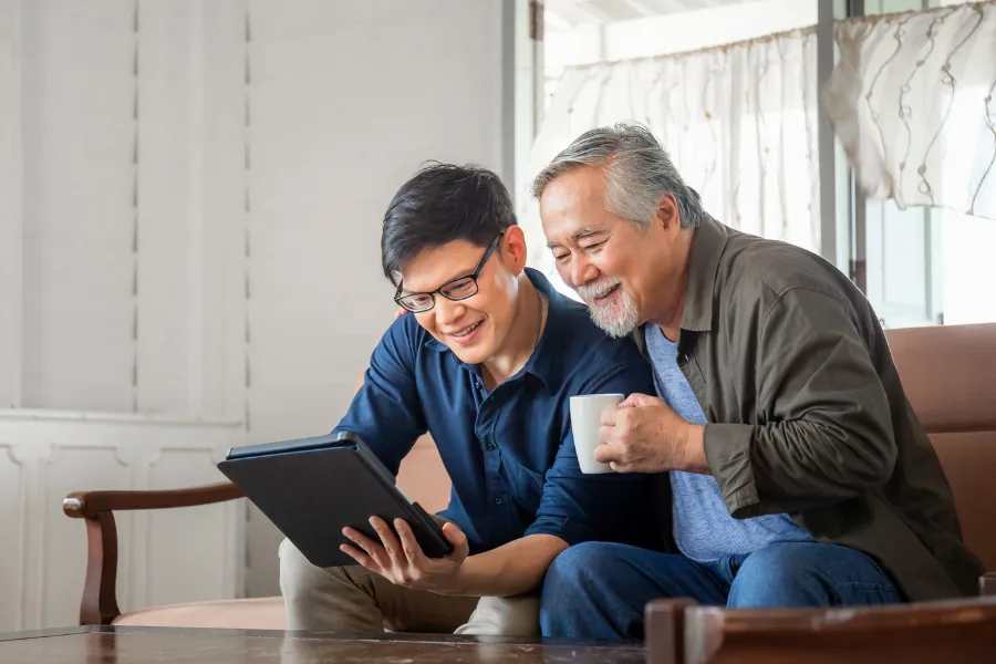 Older man holding a coffee mug with younger man holding ipad